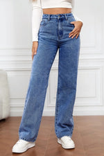 Person wearing blue jeans and white sneakers in a minimalistic setting