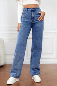 Person wearing blue jeans and white sneakers in a minimalistic setting