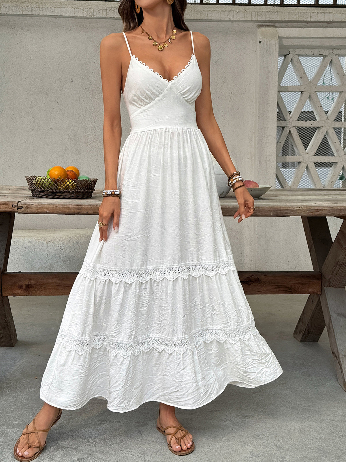 Woman wearing a white dress standing outdoors near a wooden table with fruits.