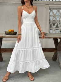 Woman wearing a white dress standing outdoors near a wooden table with fruits.