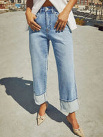Person wearing light blue jeans on a rooftop with a blurred cityscape background