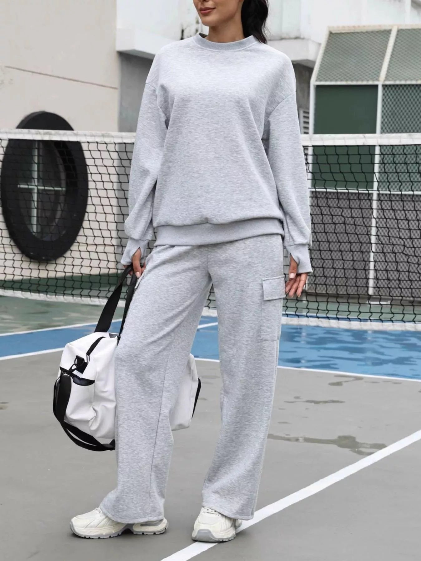 Person wearing a gray tracksuit on a tennis court