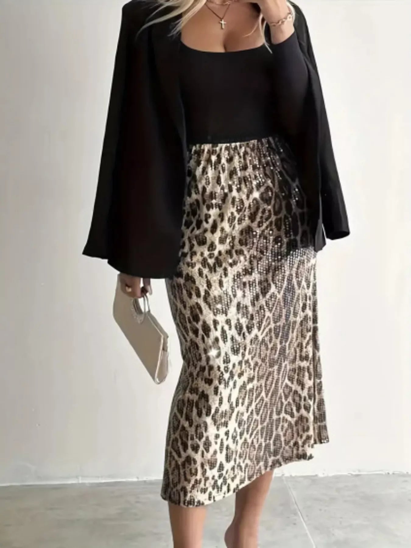 Person wearing a black top and leopard print skirt with a plain background
