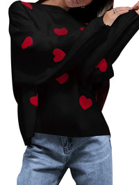 Black sweater with red heart patterns worn by a person, on a white background