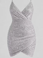 A silver sequined mini dress with a crossover wrap-style bodice and draped skirt, shown against a solid gray background.