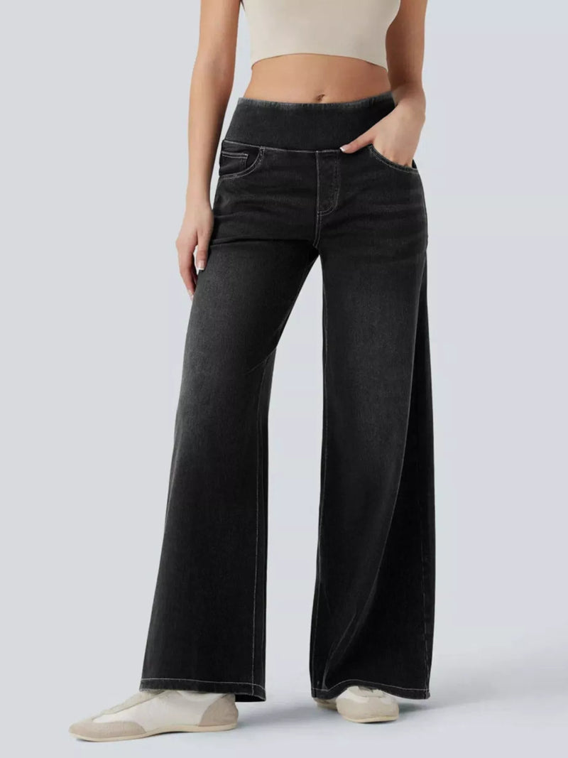 Person wearing black wide-leg jeans on a white background