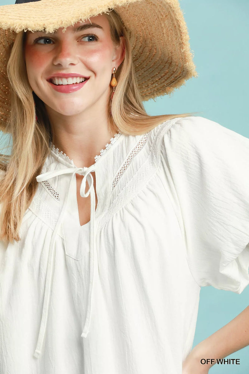 Woman wearing a white blouse and straw hat against a light blue background