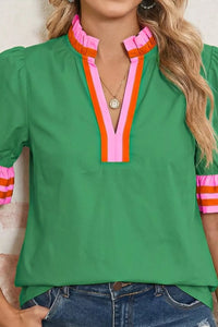 Green top with colorful neckline and sleeves worn by a person.