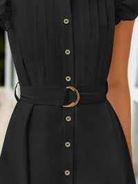Black dress with gold buttons and belt on a blurred background