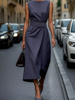 Woman in a navy dress walking on a city street.