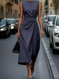Woman in a navy dress walking on a city street.