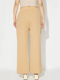 Person wearing beige high-waisted pants on a white background