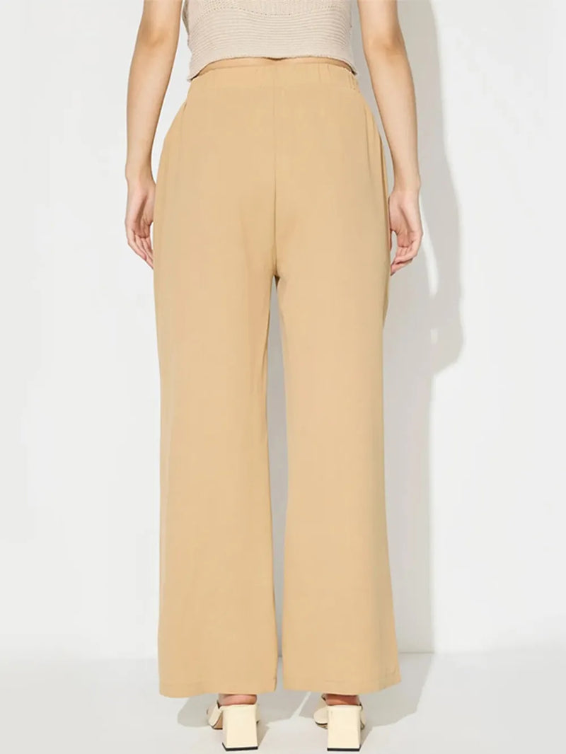 Person wearing beige high-waisted pants on a white background