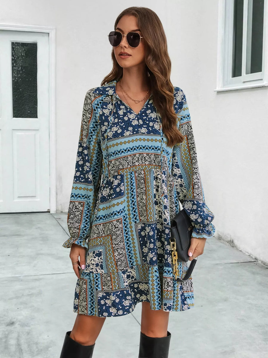 Woman wearing a patterned dress with long sleeves in an outdoor setting.