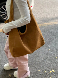Person holding a brown tote bag on a street