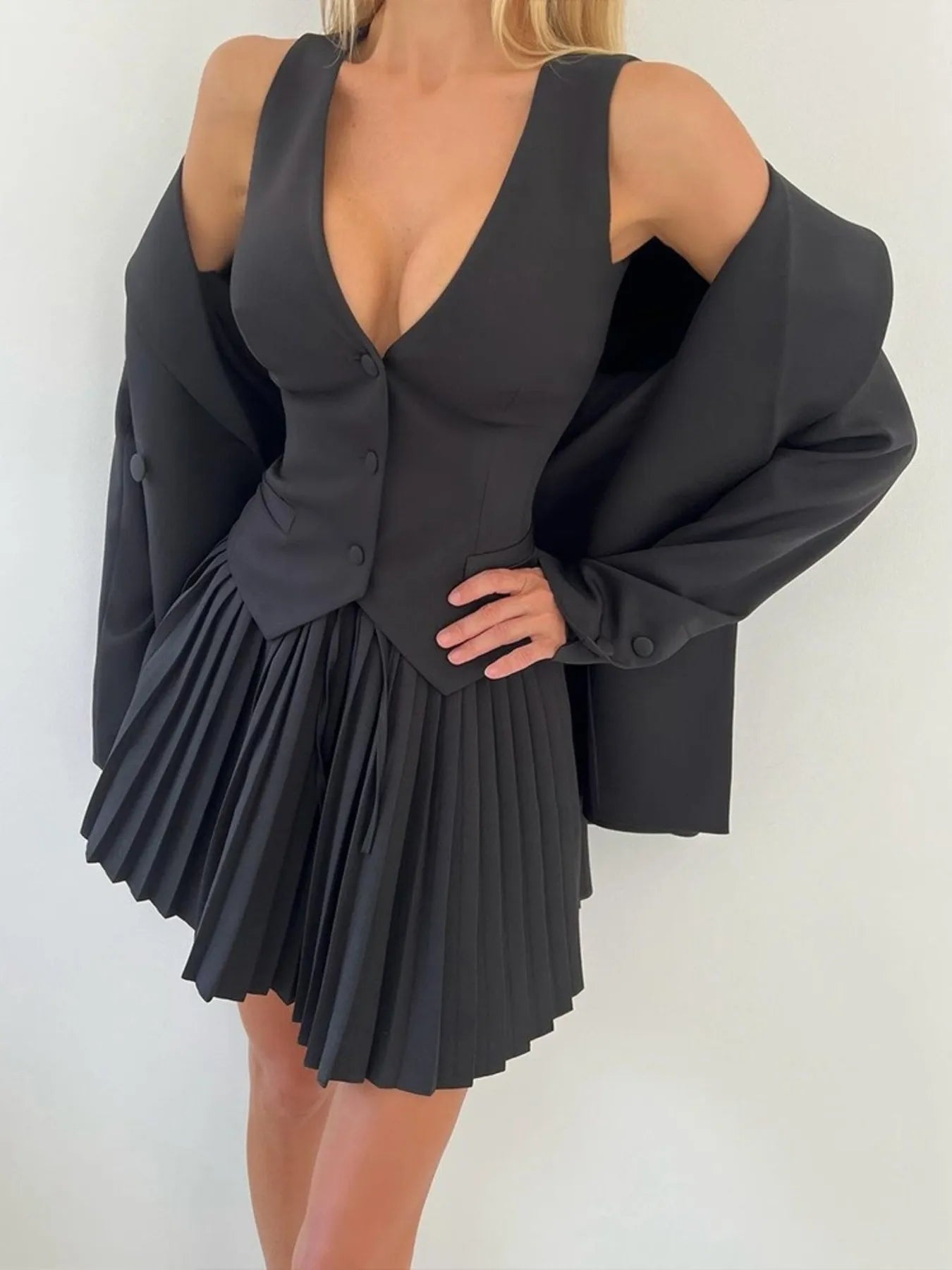 Black pleated dress with a blazer over it on a white background