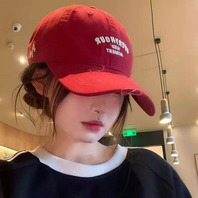 Person wearing a red cap indoors with visible ceiling lights.