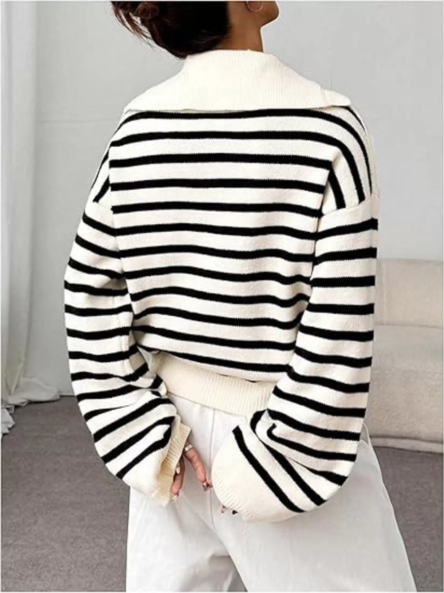 Person wearing a black and white striped sweater with a plain background