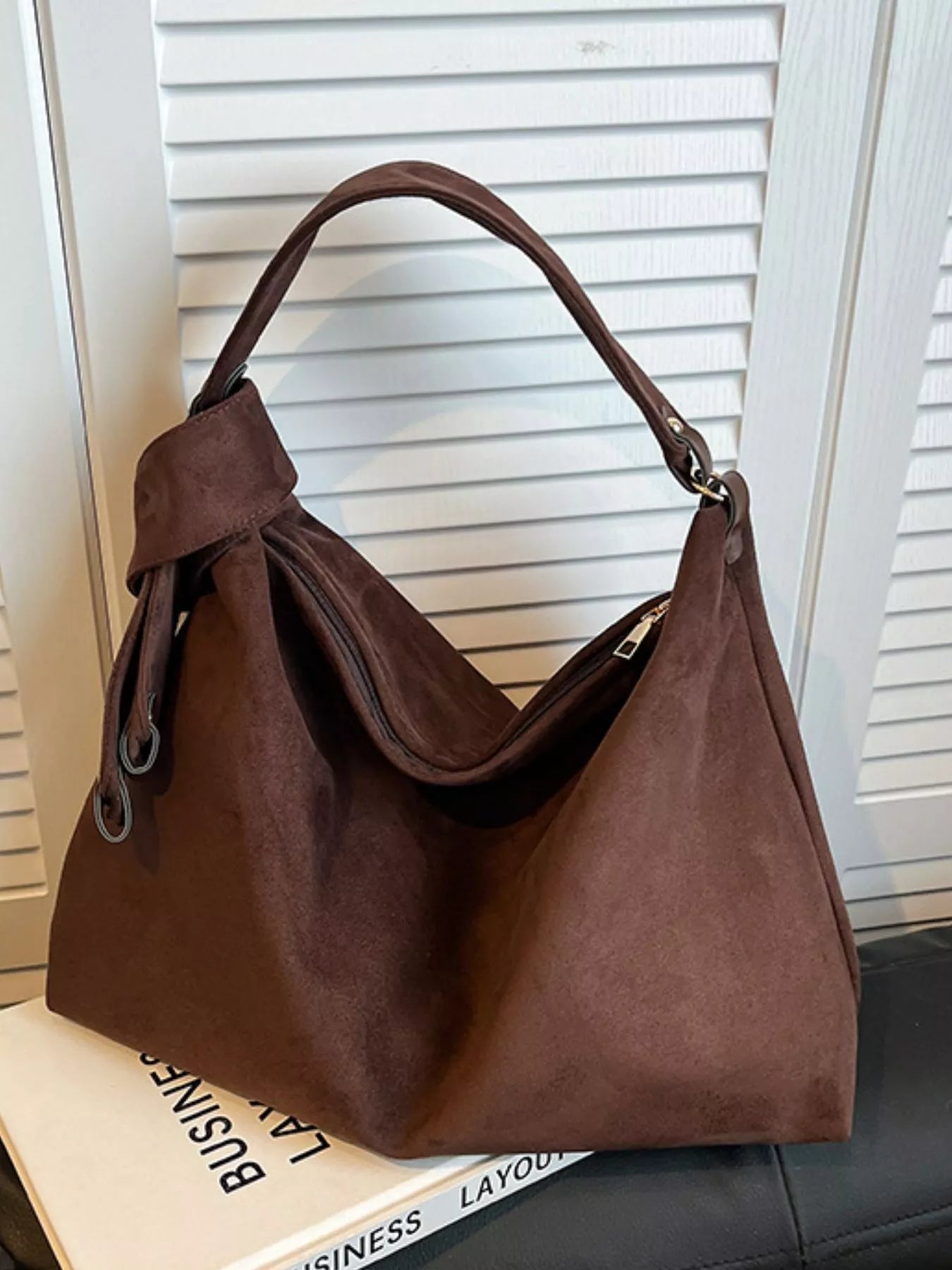 Brown handbag on a surface with a window blind background