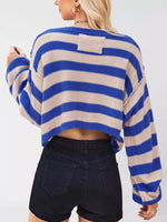 Person wearing a blue and beige striped sweater with black shorts on a white background