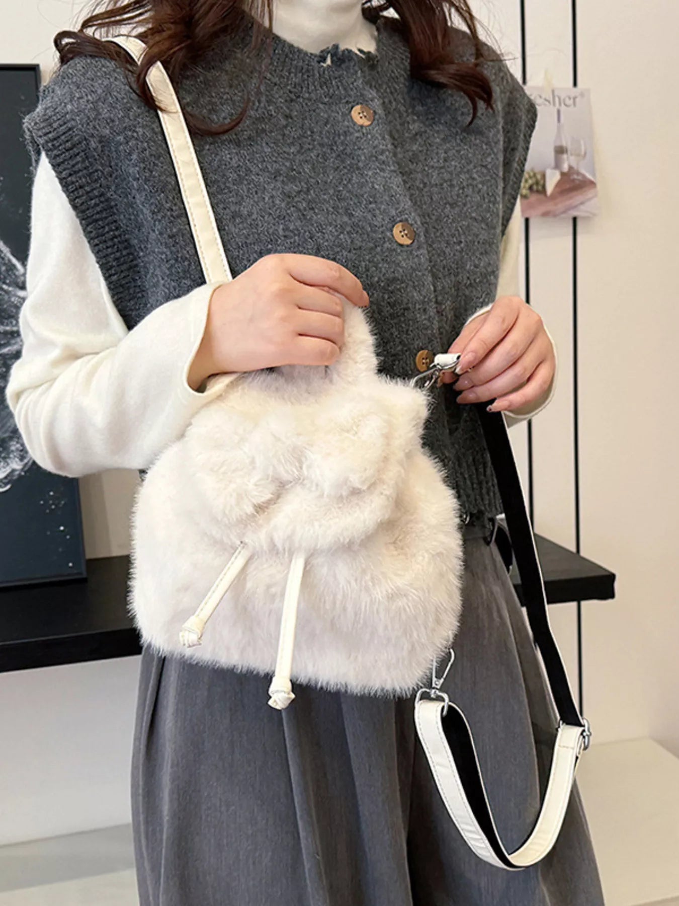 Person holding a white fluffy bag with a gray vest and white shirt