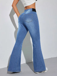 Blue flared jeans worn by a person on a plain background