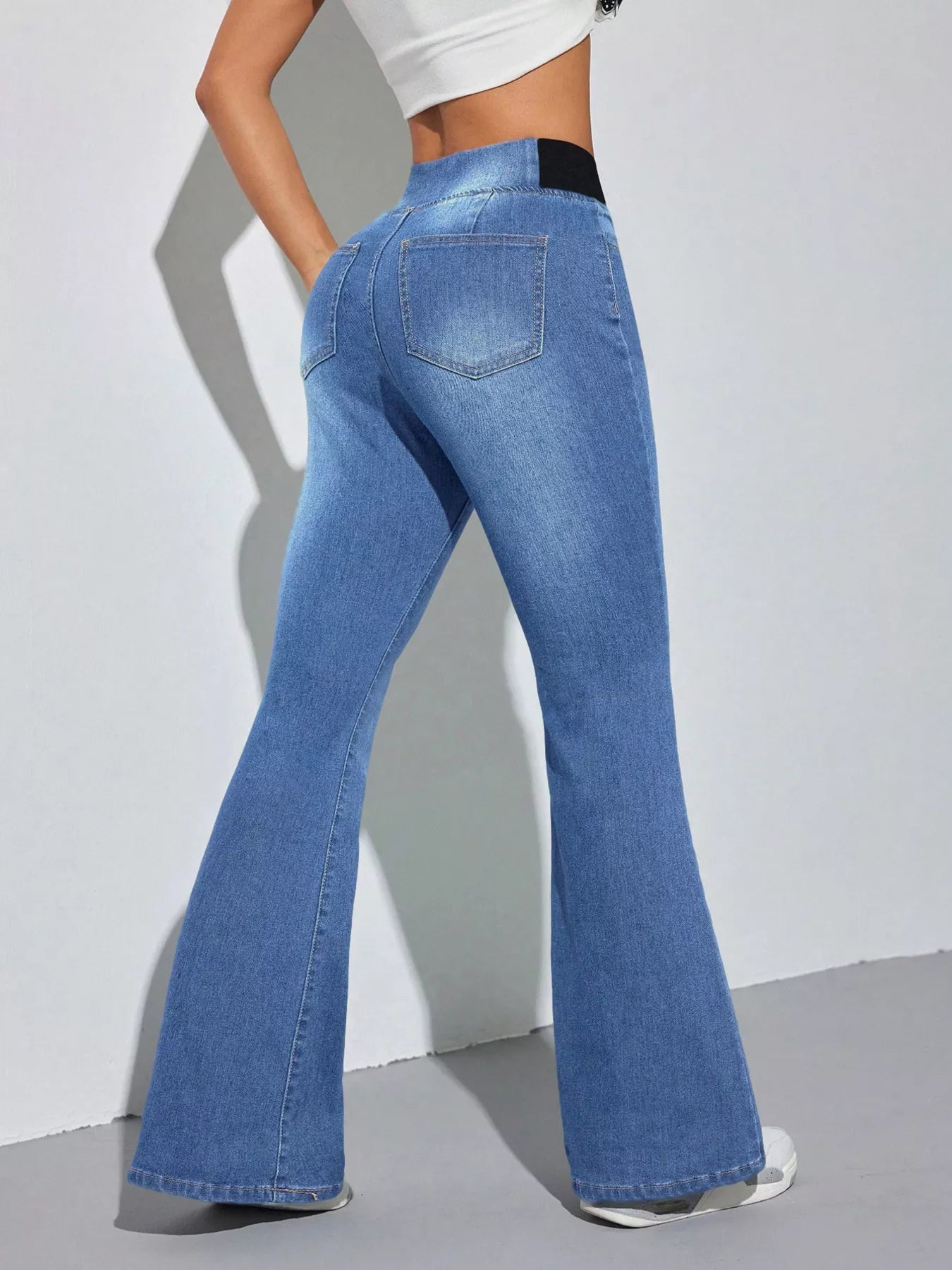 Blue flared jeans worn by a person on a plain background
