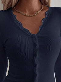 Navy blue long-sleeve top with lace detailing on a plain background