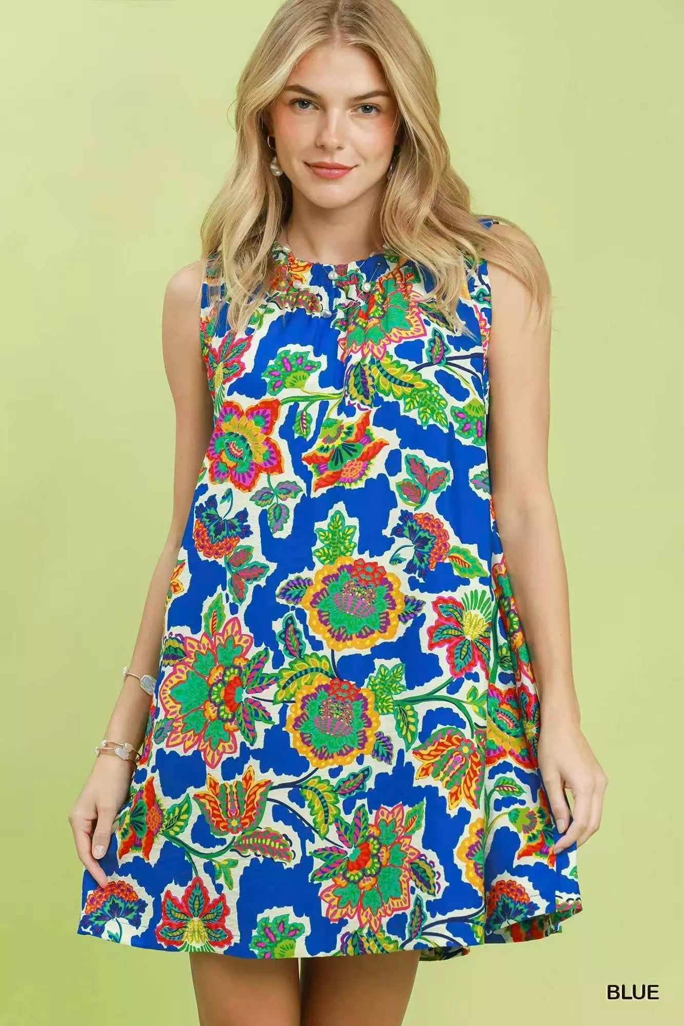 Woman wearing a colorful floral dress on a green background