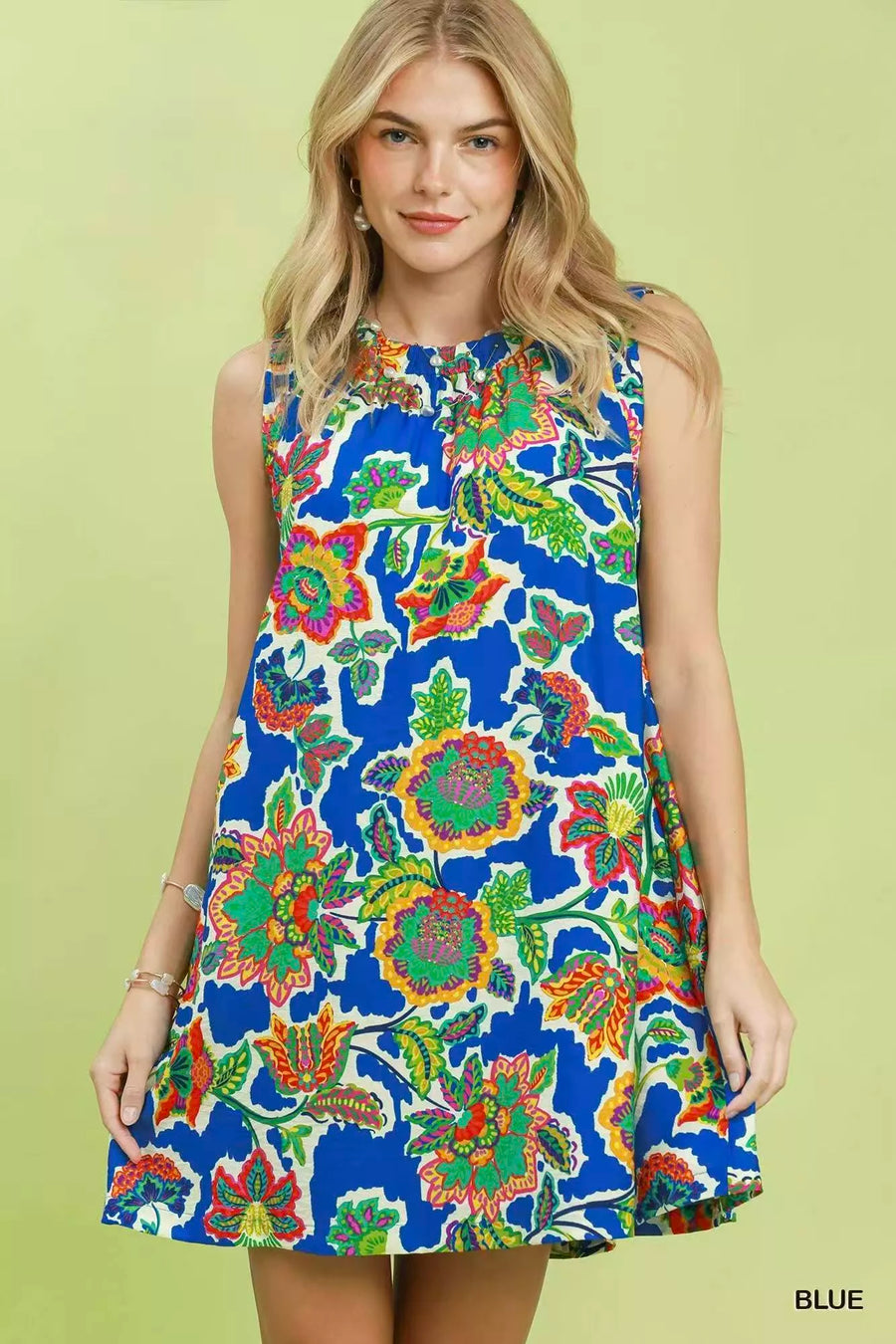 Woman wearing a colorful floral dress on a green background