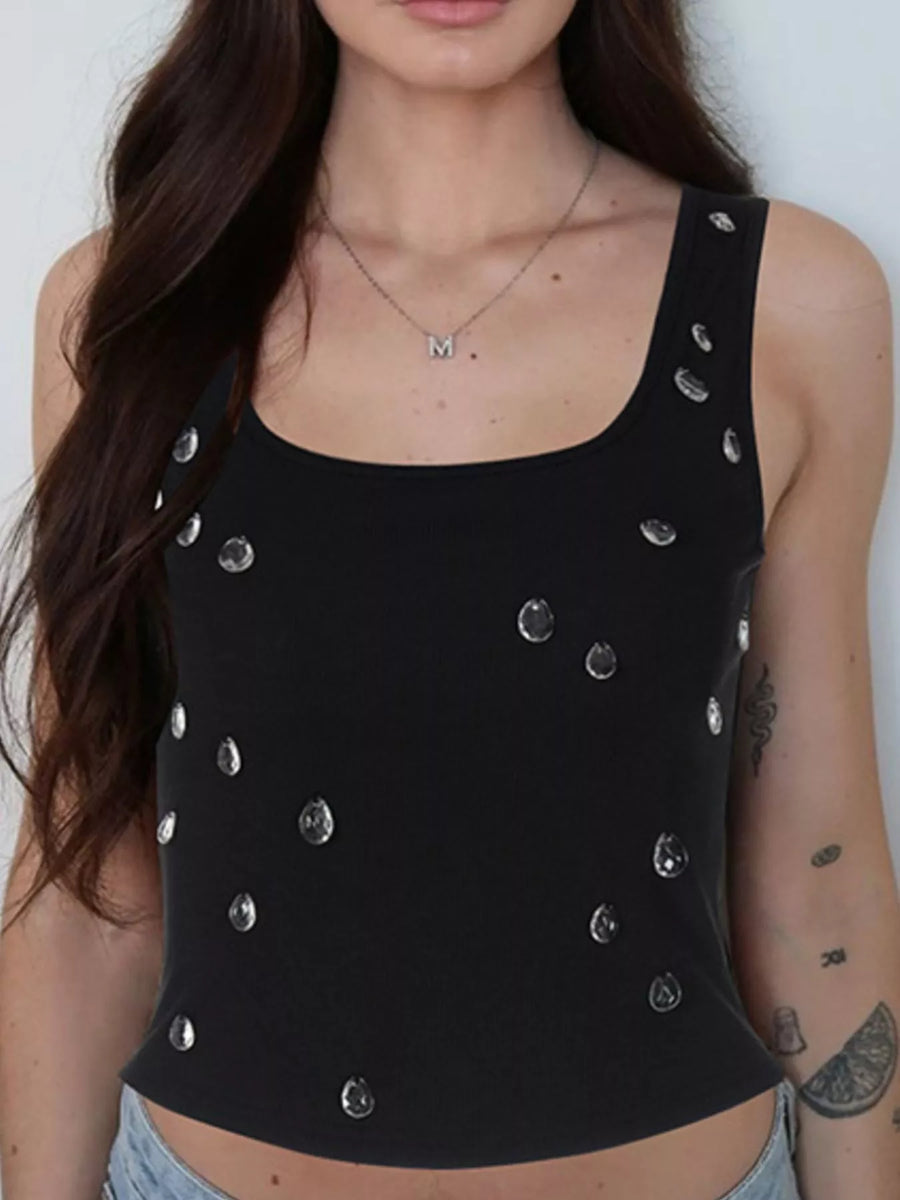 Black tank top with silver embellishments worn by a person against a white background