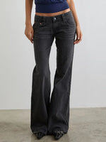 Person wearing black flared jeans against a plain background