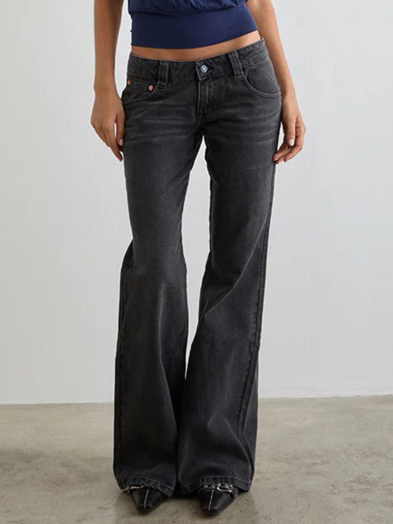 Person wearing black flared jeans against a plain background
