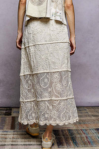 Person wearing a layered lace dress on a textured floor with a neutral background