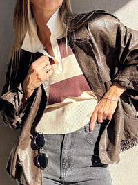 Person wearing a brown leather jacket over a striped shirt with sunglasses hanging from the collar.