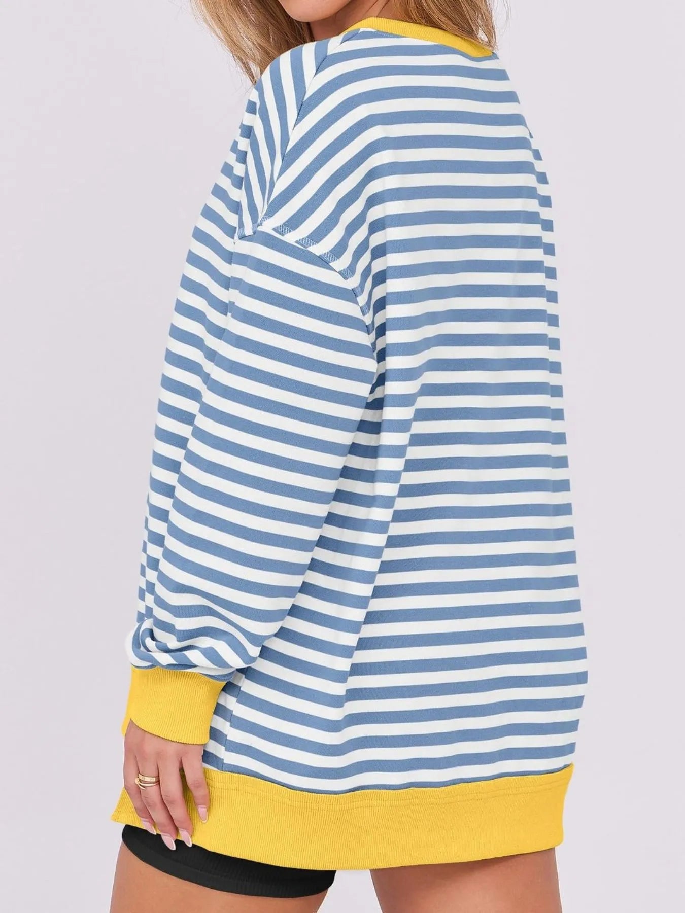 Blue and white striped shirt with yellow trim worn by a person on a light gray background