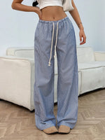 Person wearing blue and white striped pants with a white top in a living room setting.
