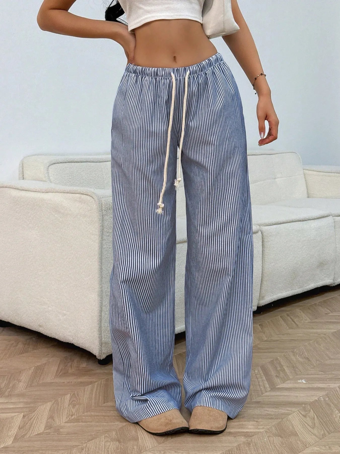 Person wearing blue and white striped pants with a white top in a living room setting.