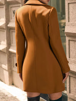 Person wearing a mustard yellow coat standing against a textured wall.