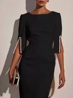 Black dress with pearl shoulder details on a neutral background