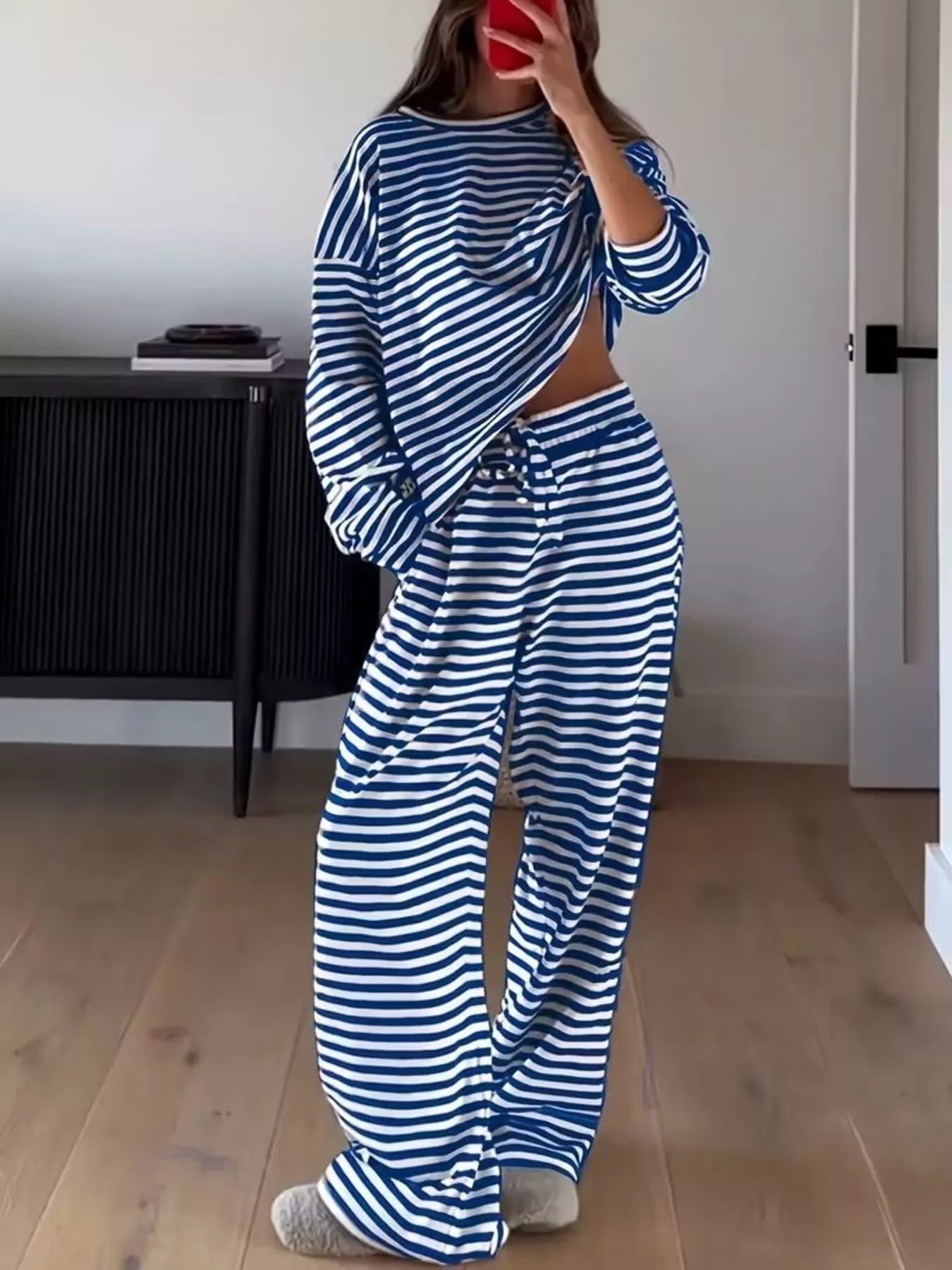 Person wearing a blue and white striped outfit in a room with wooden flooring and a black cabinet.