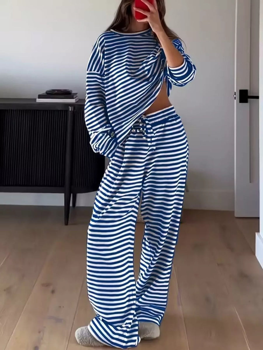 Person wearing a blue and white striped outfit in a room with wooden flooring and a black cabinet.