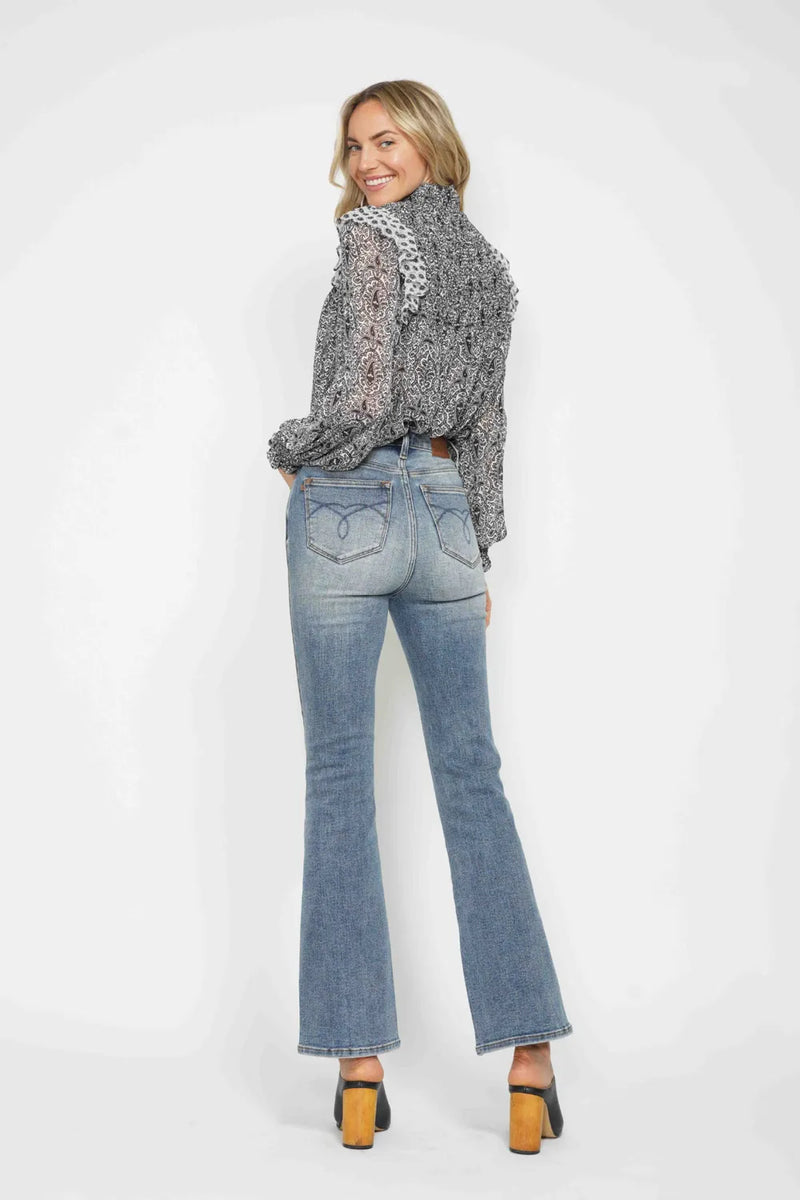 Woman wearing a patterned blouse and blue jeans on a white background