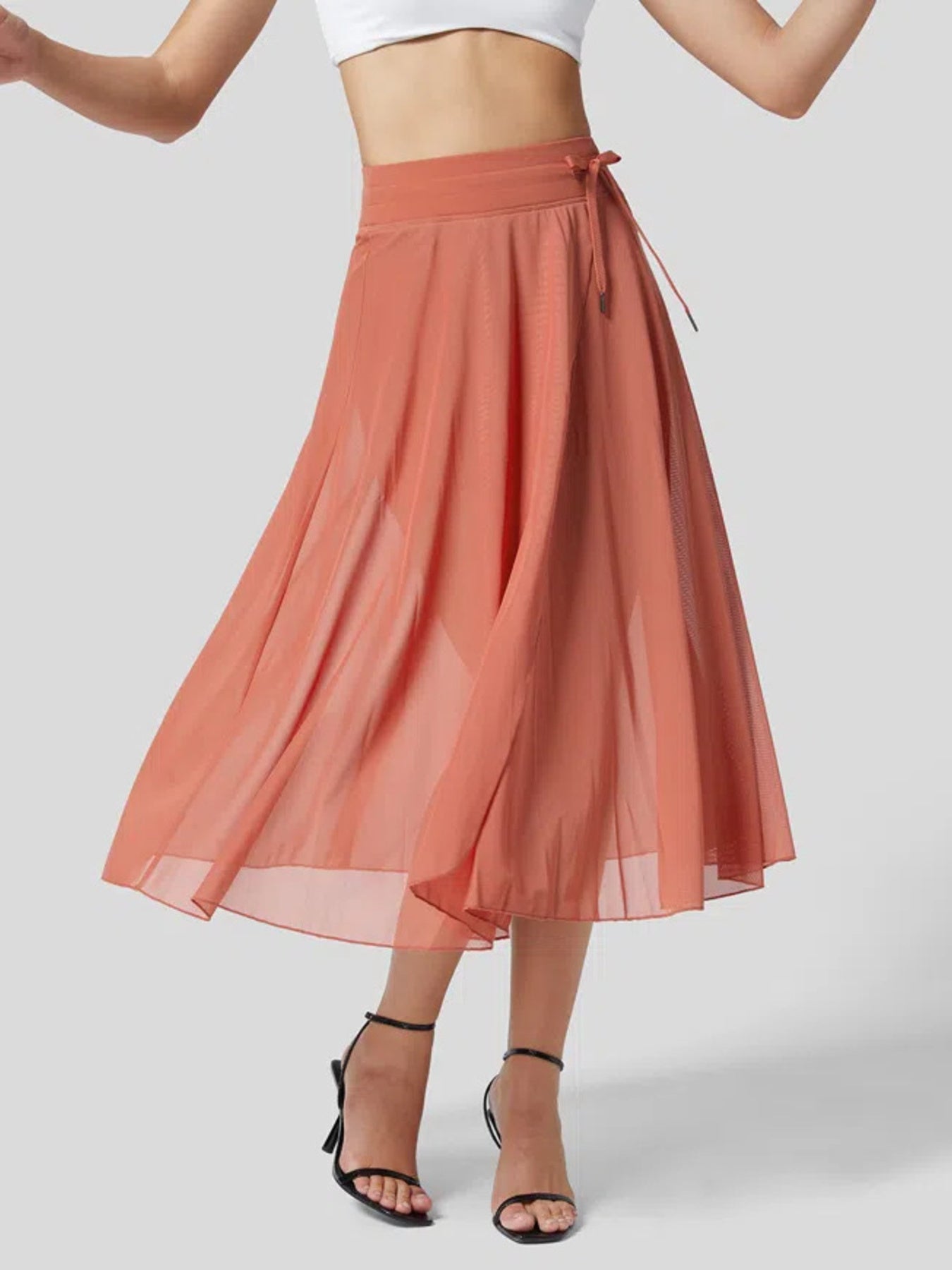 Coral skirt worn by a person on a plain background