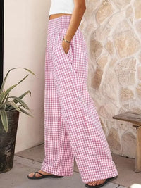 Person wearing pink checkered pants standing against a stone wall.