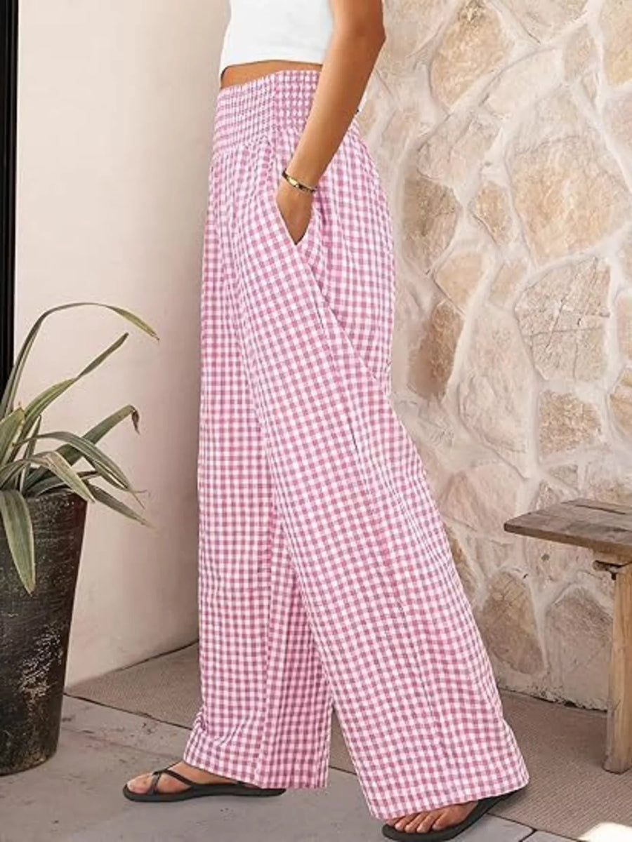 Person wearing pink checkered pants standing against a stone wall.