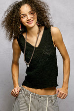 Woman wearing a black sleeveless top and striped pants against a gray background
