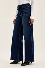 Person wearing dark blue wide-leg jeans on a white background