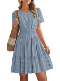 Woman wearing a blue dress holding a woven bag on a white background