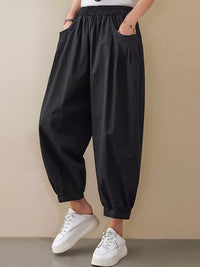 Person wearing black wide-leg pants and white sneakers on a beige background